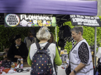 Zwei Frauen stehen vor einem bunt geschmückten Stand. Im Pavillion stehen mehrere Frauen